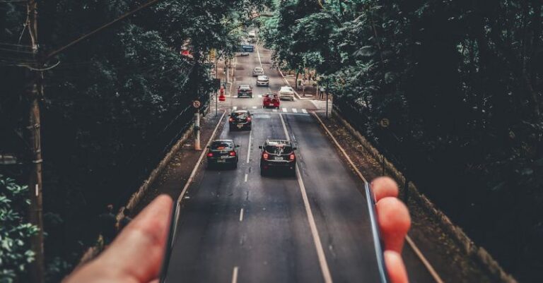 Cars - Forced Perspective Photography of Cars Running on Road Below Smartphone